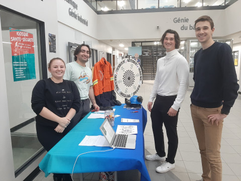 Quatre étudiants en Environnement, hygiène et sécurité au travail autour d'un stand d'information.