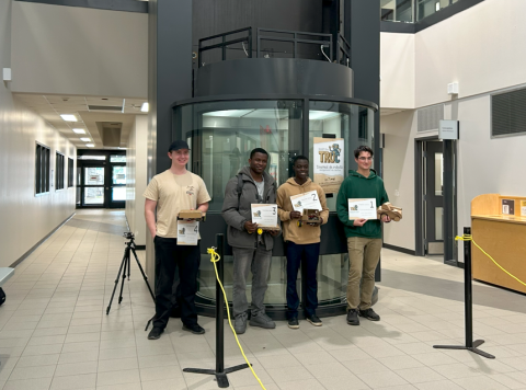 Quatre étudiants recevant leur prix lors du tournoi de robots uniquement en carton.