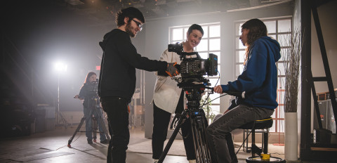 Trois étudiants travaillent autout d'une caméra lors d'un tournage