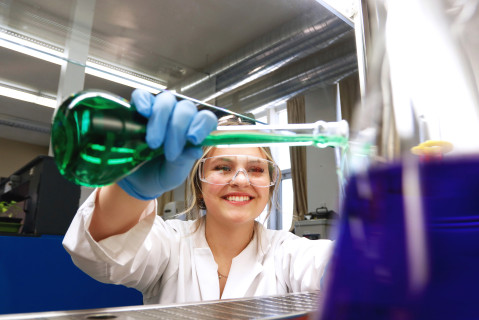 Une étudiante tout sourire verse du liquide à partir d'une fiole