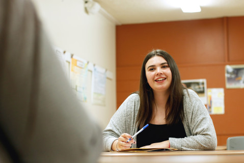 Une étudiante est assise à une table un crayon à la main